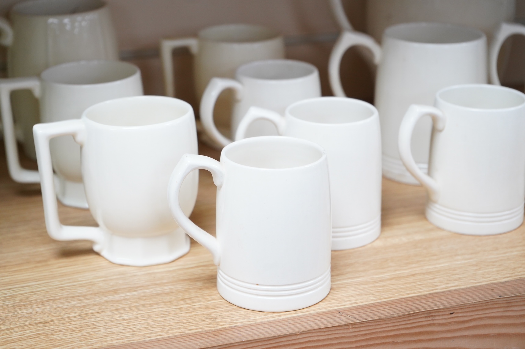 Keith Murray for Wedgwood, a cream lemonade jug, five small mugs, two large three faceted, largest 21cm high (12)